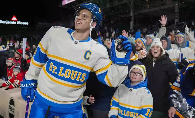 St. Louis Blues center Brayden Schenn, left, celebrates with fans after his team's win over the Chicago Blackhawks in the NHL Winter Classic outdoor hockey game at Wrigley Field, Tuesday, Dec. 31, 2024, in Chicago. (AP Photo/Erin Hooley)