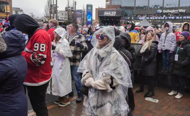 Fans watch pregame entertainment in the rain before the NHL Winter Classic outdoor hockey game between the Chicago Blackhawks and St. Louis Blues at Wrigley Field, Tuesday, Dec. 31, 2024, in Chicago. (AP Photo/Erin Hooley)