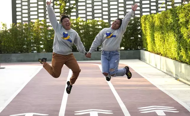 Nutanong sopon, 43, left, and Jutarat chuenpae, 37, both business owners, hold hands and jump for a photograph in Bangkok, Thailand, Sunday, Jan. 12, 2025, (AP Photo/Sakchai Lalit)