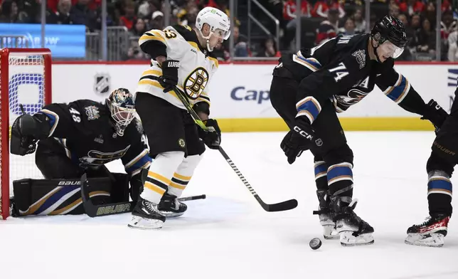 Boston Bruins left wing Brad Marchand (63) battles for the puck against Washington Capitals defenseman John Carlson (74) and goaltender Logan Thompson (48) during the second period of an NHL hockey game, Tuesday, Dec. 31, 2024, in Washington. (AP Photo/Nick Wass)