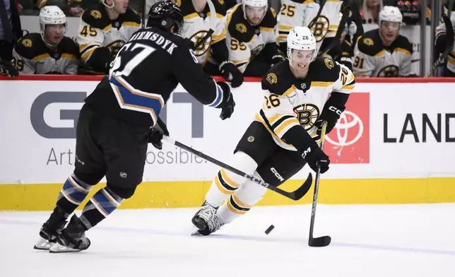 Boston Bruins center Marc McLaughlin (26) skates with the puck against Washington Capitals defenseman Trevor van Riemsdyk (57) during the second period of an NHL hockey game, Tuesday, Dec. 31, 2024, in Washington. (AP Photo/Nick Wass)