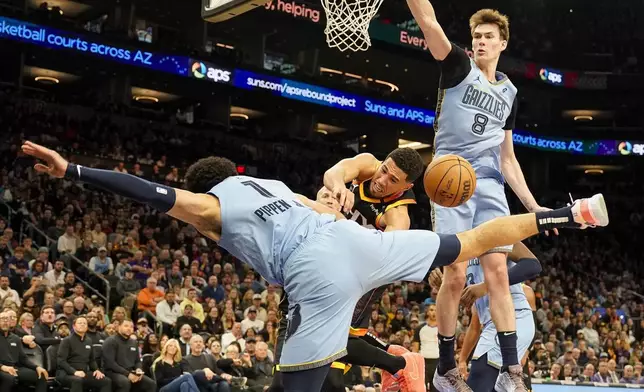 Phoenix Suns guard Devin Booker, center, loses the ball while being pressured by Memphis Grizzlies guard Scotty Pippen Jr., left, and center Colin Castleton (8) during the second half of an NBA basketball game Tuesday, Dec. 31, 2024, in Phoenix. (AP Photo/Darryl Webb)