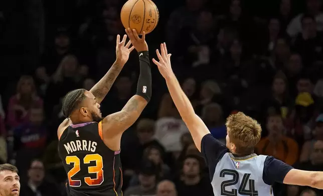 Phoenix Suns guard Monte Morris (23) shoots over Memphis Grizzlies guard Cam Spencer (24) during the first half of an NBA basketball game Tuesday, Dec. 31, 2024, in Phoenix. (AP Photo/Darryl Webb)