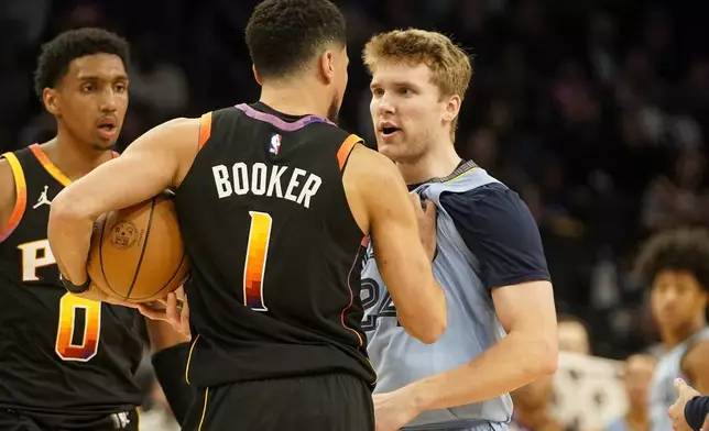 Phoenix Suns guard Devin Booker (1) and Memphis Grizzlies guard Cam Spencer (24) have words during the second half of an NBA basketball game Tuesday, Dec. 31, 2024, in Phoenix. (AP Photo/Darryl Webb)