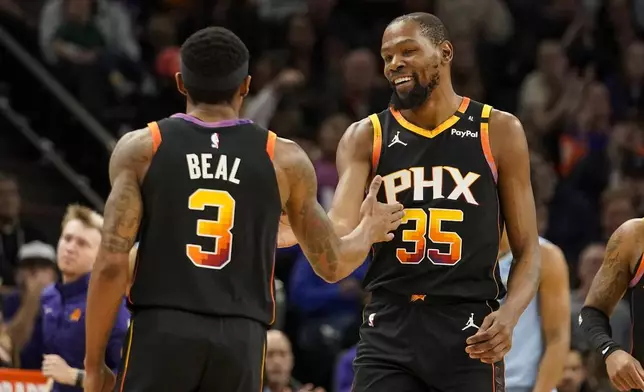 Phoenix Suns guard Bradley Beal (3) Kevin Durant (35) slap hands during the first half of an NBA basketball game against the Memphis Grizzlies Tuesday, Dec. 31, 2024, in Phoenix. (AP Photo/Darryl Webb)