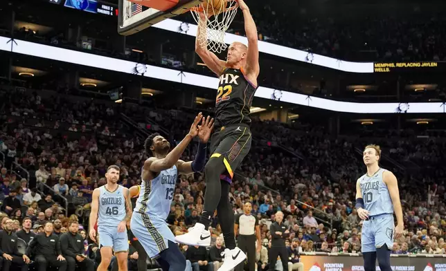 Phoenix Suns center Mason Plumlee (22) dunks against Memphis Grizzlies players John Konchar, left, Jaren Jackson Jr., middle, and Luke Kennard, right, during the second half of an NBA basketball game Tuesday, Dec. 31, 2024, in Phoenix. Memphis won 117-112. (AP Photo/Darryl Webb)