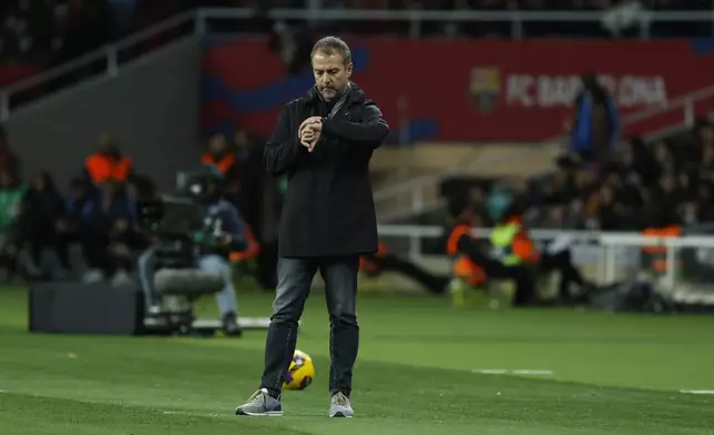 Barcelona's head coach Hansi Flick checks his watches during the Spanish La Liga soccer match between Barcelona and Valencia at the Lluis Companys Olympic Stadium in Barcelona, Spain, Sunday, Jan. 26, 2025. (AP Photo/Joan Monfort)