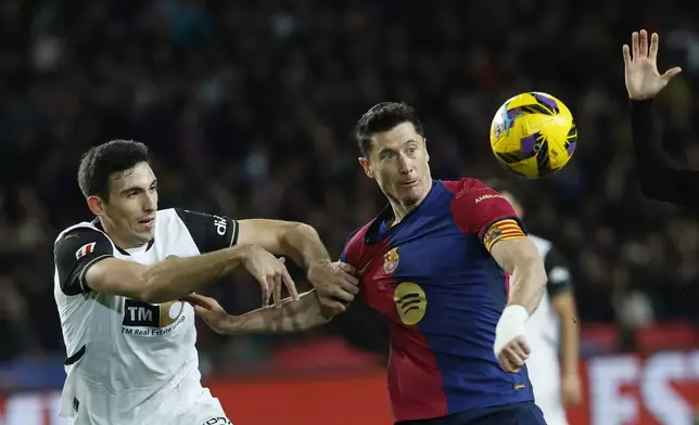 Valencia's Cesar Tarrega, left, and Barcelona's Robert Lewandowski challenge for the ball during the Spanish La Liga soccer match between Barcelona and Valencia at the Lluis Companys Olympic Stadium in Barcelona, Spain, Sunday, Jan. 26, 2025. (AP Photo/Joan Monfort)