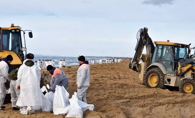 In this photo released by Krasnodar Gov. Veniamin Kondratyev in his Telegram channel on Sunday, Jan. 5, 2025, rescuers and volunteers work to clean up tons of fuel oil that spilled out of two storm-stricken tankers more than two weeks ago in the Kerch Strait, near Anapa in Russia's southern Krasnodar region. (Krasnodar Gov. Veniamin Kondratyev Telegram channel via AP)