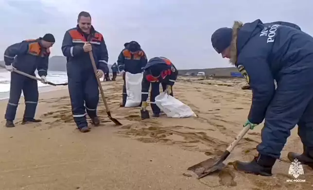 In this photo taken from video released by Russian Emergency Ministry Press Service on Saturday, Jan. 4, 2025, rescuers work to clean up tons of fuel oil that spilled out of two storm-stricken tankers more than two weeks ago in the Kerch Strait, in Russia's southern Krasnodar region. (Russian Emergency Ministry Press Service via AP)