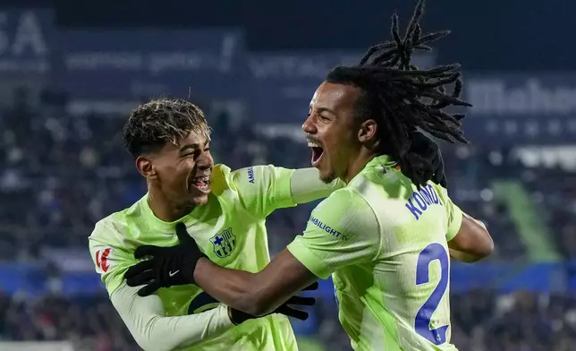 Barcelona's Jules Kounde, right, celebrates with Lamine Yamal after he scoring the opening goal against Getafe during a Spanish La Liga soccer match at the Coliseum Alfonso Perez stadium in Getafe, Spain, Saturday, Jan. 18, 2025. (AP Photo/Manu Fernandez)