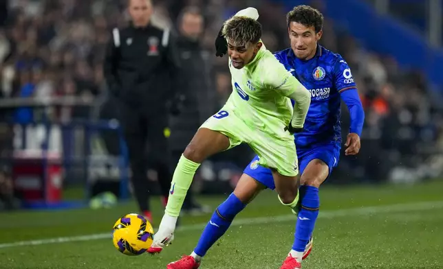Barcelona's Lamine Yamal, front, controls a ball chased by Getafe's Luis Milla during a Spanish La Liga soccer match at the Coliseum Alfonso Perez stadium in Getafe, Spain, Saturday, Jan. 18, 2025. (AP Photo/Manu Fernandez)