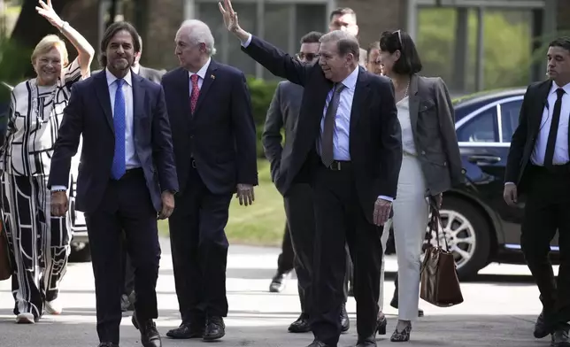 Venezuela's opposition leader Edmundo Gonzalez Urrutia, right, waves to supporters beside Uruguayan President Luis Lacalle Pou in Montevideo, Uruguay, Saturday, Jan. 4, 2025. Gonzalez, who claims he won the 2024 presidential election and is recognized by some countries as the legitimate president-elect, traveled from exile in Madrid to Argentina and Uruguay. (AP Photo/Matilde Campodonico)