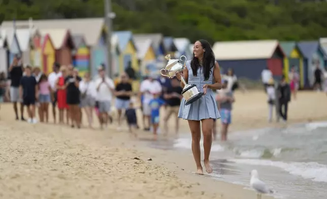 Madison Keys of the U.S. walks along Brighton Beach carrying the Daphne Akhurst Memorial Cup the morning after defeating Aryna Sabalenka of Belarus in the women's singles final at the Australian Open tennis championship in Melbourne, Australia, Sunday, Jan. 26, 2025. (AP Photo/Ng Han Guan)