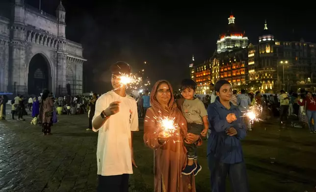 People light fireworks as they celebrate New Year's Eve near the iconic Gate way of India, in Mumbai, India, Tuesday, Dec. 31, 2024. (AP Photo/Rafiq Maqbool)