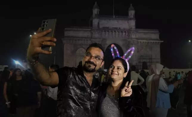 A couple make a selfie as they celebrate New Year's Eve near the iconic Gateway of India in Mumbai, India, Tuesday, Dec. 31, 2024. (AP Photo/Rafiq Maqbool)