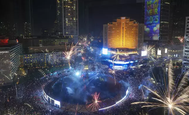 Fireworks explode as thousands of people gather in the main business district on New Year's Eve in Jakarta, Indonesia, Tuesday, Dec. 31, 2024. (AP Photo/Tatan Syuflana)