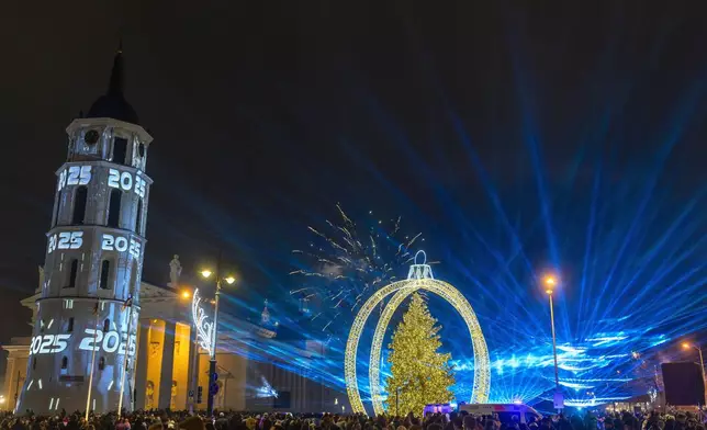 People celebrate New Year at the Cathedral Square in Vilnius, Lithuania, early Wednesday, Jan. 1, 2025. (AP Photo/Mindaugas Kulbis)