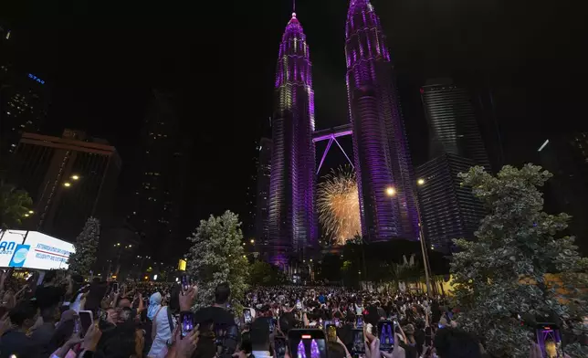 People take smartphones photos of the fireworks exploding near the Petronas Twin Towers during the New Year's celebrations in Kuala Lumpur, Malaysia, Wednesday, Jan. 1, 2025. (AP Photo/Andy Wong)