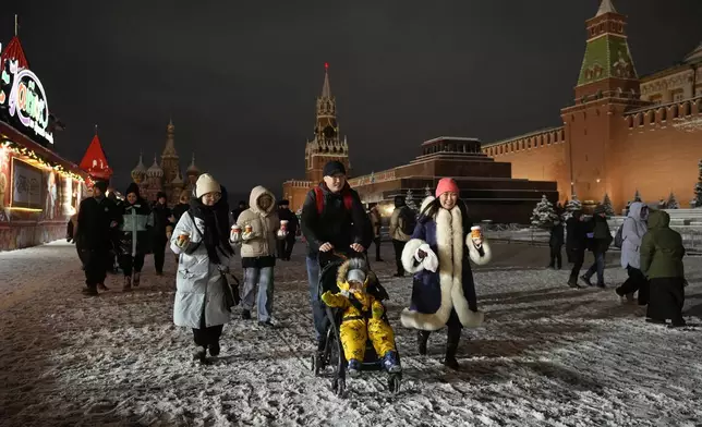 People walk in the Red Square prior to its closure for celebrations on the New Year's Eve in Moscow, Russia, Tuesday, Dec. 31, 2024. (AP Photo/Pavel Bednyakov)