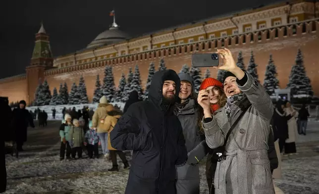 People take a selfie photo in the Red Square prior to its closure for celebrations on the New Year's Eve in Moscow, Russia, Tuesday, Dec. 31, 2024. (AP Photo/Pavel Bednyakov)