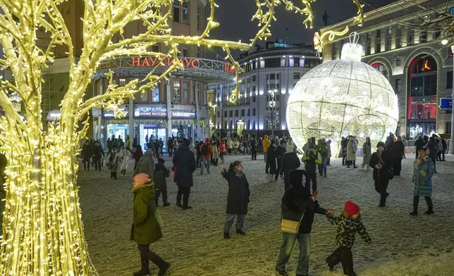 People walk near the Red Square prior to its closure for celebrations on the New Year's Eve in Moscow, Russia, Tuesday, Dec. 31, 2024. (AP Photo/Pavel Bednyakov)