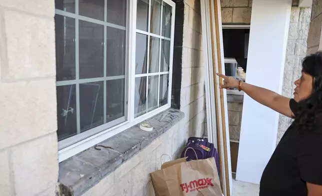 Evelyn Paguirigan points to broken windows at her home across the street from where a New Year's Eve fireworks explosion killed and injured people in Honolulu, on Wednesday, Jan. 1, 2025. (AP Photo/Marco Garcia)