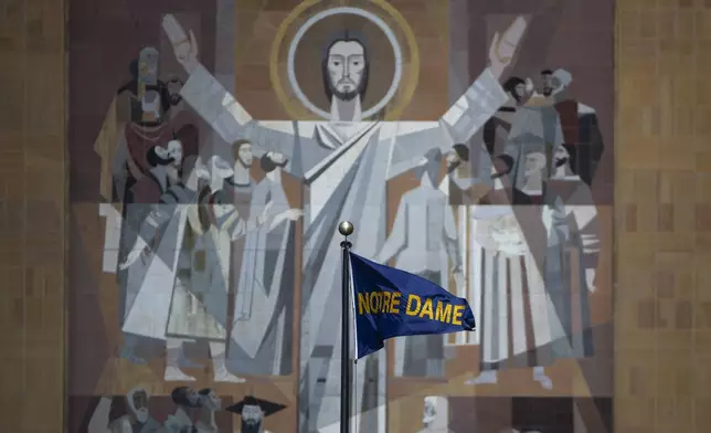 FILE - A Notre Dame flag waves in the wind in front of the The Word of Life Mural, aka "Touchdown Jesus," on the Hesburgh Library before an NCAA college football game between Notre Dame and Northern Illinois, Saturday Sept. 7, 2024, in South Bend, Ind. (AP Photo/Michael Caterina, File)