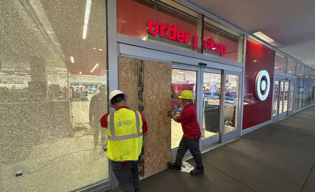 Workers secure the outside of a Target store after two security guards were shot and wounded area after they confronted a man suspected of shoplifting in downtown Los Angeles on Tuesday, Dec. 31, 2024. (AP Photo/Damian Dovarganes)