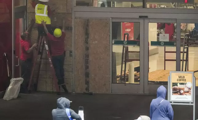 Workers secure the outside of a temporarily closed Target store after two security guards were shot and wounded after they confronted a man suspected of shoplifting in downtown Los Angeles on Tuesday, Dec. 31, 2024. (AP Photo/Damian Dovarganes)