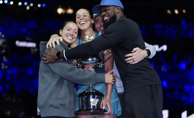 Madison Keys, center, of the U.S. is embraced by her team as she holds the Daphne Akhurst Memorial Cup after defeating Aryna Sabalenka of Belarus in the women's singles final at the Australian Open tennis championship in Melbourne, Australia, Saturday, Jan. 25, 2025. (AP Photo/Asanka Brendon Ratnayake)