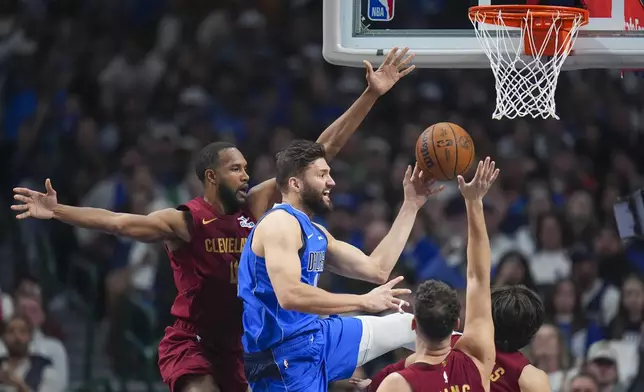 Dallas Mavericks forward Maxi Kleber, center, makes a pass as Cleveland Cavaliers forward Evan Mobley, left, and teammates defend during the first half of an NBA basketball game, Friday, Jan. 3, 2025, in Dallas. (AP Photo/Julio Cortez)