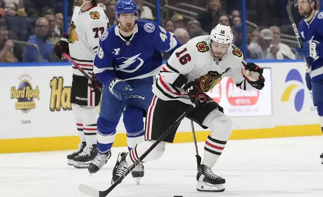 Chicago Blackhawks center Jason Dickinson (16) breaks out ahead of Tampa Bay Lightning defenseman Nick Perbix (48) during the third period of an NHL hockey game Tuesday, Jan. 28, 2025, in Tampa, Fla. (AP Photo/Chris O'Meara)