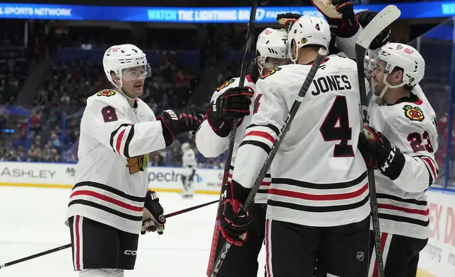 Chicago Blackhawks center Ryan Donato (8) celebrates his goal against the Tampa Bay Lightning with teammates, including, defenseman Seth Jones (4) and center Philipp Kurashev (23) during the third period of an NHL hockey game Tuesday, Jan. 28, 2025, in Tampa, Fla. (AP Photo/Chris O'Meara)
