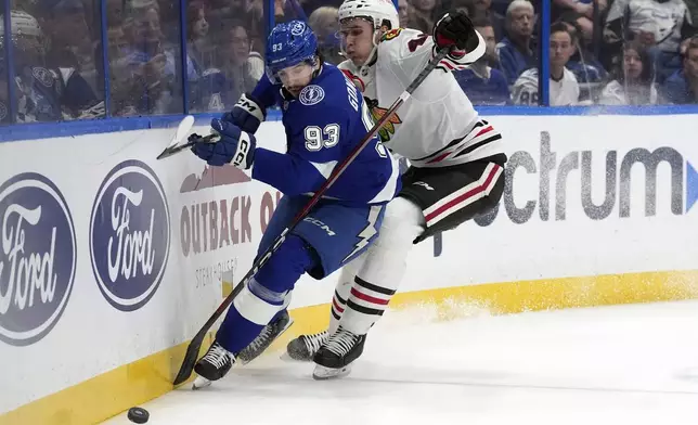 Tampa Bay Lightning center Gage Goncalves (93) and Chicago Blackhawks defenseman Louis Crevier (46) chase a lookse puck during the second period of an NHL hockey game Tuesday, Jan. 28, 2025, in Tampa, Fla. (AP Photo/Chris O'Meara)