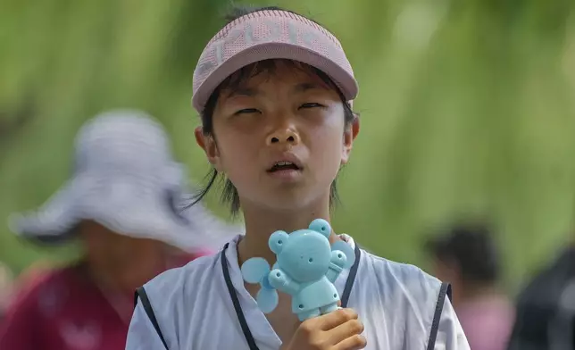 FILE - A child holds an electric fan as they react to the heat during a visit to the Forbidden City in Beijing, July 8, 2024. (AP Photo/Andy Wong, File)