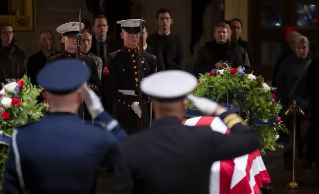 A military honor guard salutes as mourners view the flag-draped casket of former President Jimmy Carter as he lies in state in the Rotunda, at the Capitol in Washington, Tuesday, Jan. 7, 2025. (AP Photo/Ben Curtis)