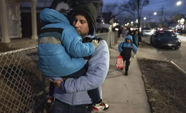 Gabriel Montilla carries his son after picking up his children from their school in the Flatbush neighborhood of Brooklyn and commuting with them to a shelter in the Jamaica neighborhood of the Queens borough of New York, Tuesday, Jan. 14, 2025. Montilla and his family were recently relocated to a migrant shelter in Queens after the family shelter at Floyd Bennett Field was closed. (AP Photo/Klaus Galiano)