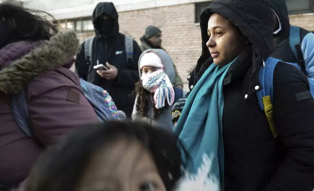 Gleydis Carvajal waits in line with her children to board a bus after picking up his children from their school in the Flatbush neighborhood of Brooklyn and commuting with them to a shelter in the Jamaica neighborhood of the Queens borough of New York, Tuesday, Jan. 14, 2025. Carvajal and her family were recently relocated to a migrant shelter in Queens after the family shelter at Floyd Bennett Field was closed. (AP Photo/Klaus Galiano)