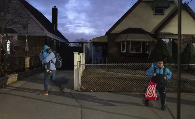 Gabriel Montilla carries his son from a bus stop to a migrant shelter in Queens after picking them up from school in Brooklyn, in New York, Tuesday, Jan. 14, 2025. Montilla and his family were recently relocated to a migrant shelter in Queens after the family shelter at Floyd Bennett Field was closed. (AP Photo/Klaus Galiano)