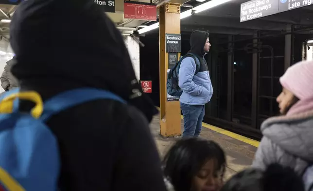 Gabriel Montilla waits for a train after picking up his children from their school in the Flatbush neighborhood of Brooklyn and commuting with them to a shelter in the Jamaica neighborhood of the Queens borough of New York, Tuesday, Jan. 14, 2025. Montilla and his family were recently relocated to a migrant shelter in Queens after the family shelter at Floyd Bennett Field was closed. (AP Photo/Klaus Galiano)