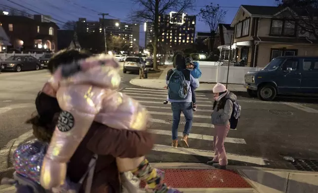 Gleydis Carvajal, left, and her husband, Gabriel Montilla, carry their children from a bus stop to a migrant shelter in Queens after picking them up from school in Brooklyn, in New York, Tuesday, Jan. 14, 2025. Carvajal and her family were recently relocated to a migrant shelter in Queens after the family shelter at Floyd Bennett Field was closed. (AP Photo/Klaus Galiano)