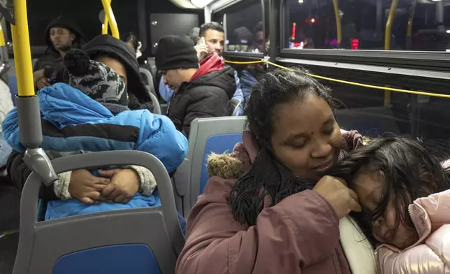 Ecuadorian Leidy Andrade rides a bus with her daughter as they return to a shelter in the Jamaica neighborhood of the Queens borough of New York, Tuesday, Jan. 14, 2025, after picking up her daughter from a school in Brooklyn. Andrade and her family were recently relocated to a migrant shelter in Queens after the family shelter at Floyd Bennett Field was closed. (AP Photo/Klaus Galiano)