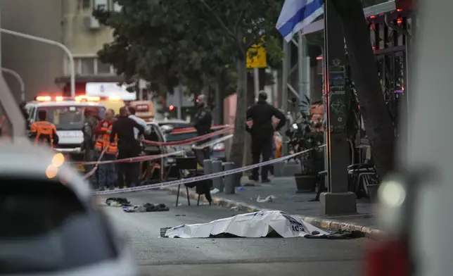 The body of a man who attacked pedestrians with a knife lies covered on the street after he was shot during the stabbing incident in Tel Aviv, Israel, Saturday Jan. 18, 2025.(AP Photo/Oded Balilty)