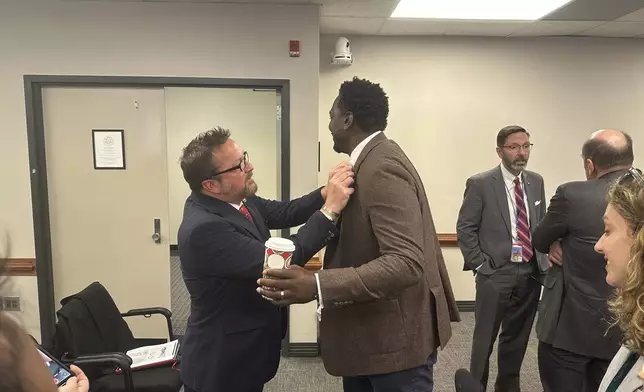 Republican South Carolina Rep. Brandon Cox from Goose Creek, left, adjusts the House pin on the lapel of Democratic state Rep. Jermaine Johnson of Columbia, right, before they talk to reporters about a proposed statue of Reconstruction hero Robert Smalls on Wednesday, Jan. 8, 2025, in Columbia, S.C. (AP Photo/Jeffrey Collins)