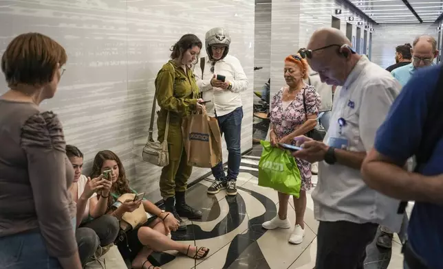 FILE.- People take cover as a siren warns of incoming rockets fired from Yemen, in Ramat Gan, Israel, Monday, Oct. 7, 2024. (AP Photo/Oded Balilty,File)