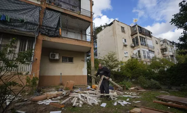 A man works next to damaged building near the site where a missile launched from Yemen landed Jaffa district, in Tel Aviv, Israel, Tuesday, Dec. 31, 2024. (AP Photo/Matias Delacroix)