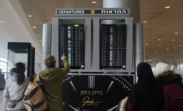 Travelers check departing flights at Ben Gurion International Airport near Tel Aviv, Israel, Tuesday, Dec. 31, 2024. (AP Photo/Matias Delacroix)