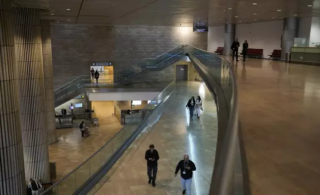 Travelers walk through the nearly empty hallways of Ben Gurion International Airport near Tel Aviv, Israel, Tuesday, Dec. 31, 2024. (AP Photo/Matias Delacroix)