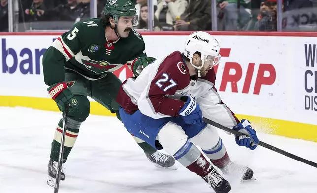 Colorado Avalanche left wing Jonathan Drouin, right, and Minnesota Wild defenseman Jake Middleton compete for the puck during the first period of an NHL hockey game Thursday, Jan. 9, 2025, in St. Paul, Minn. (AP Photo/Matt Krohn)